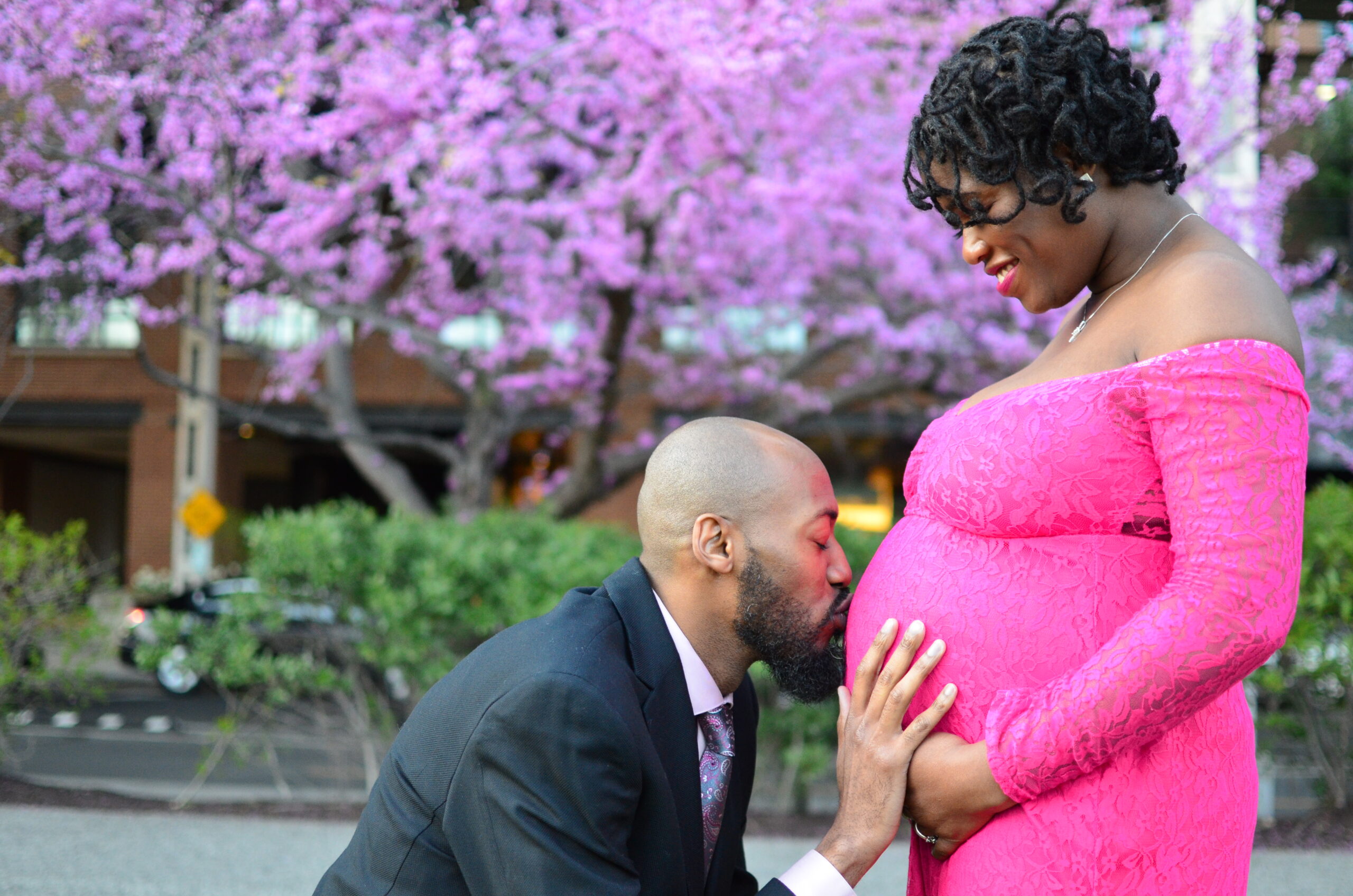 Husband stoops down to kiss wife's pregnant belly